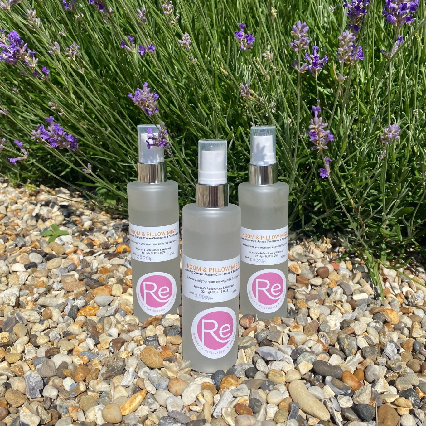 Image of room spray bottles outside on gravel next to a lavender bush
